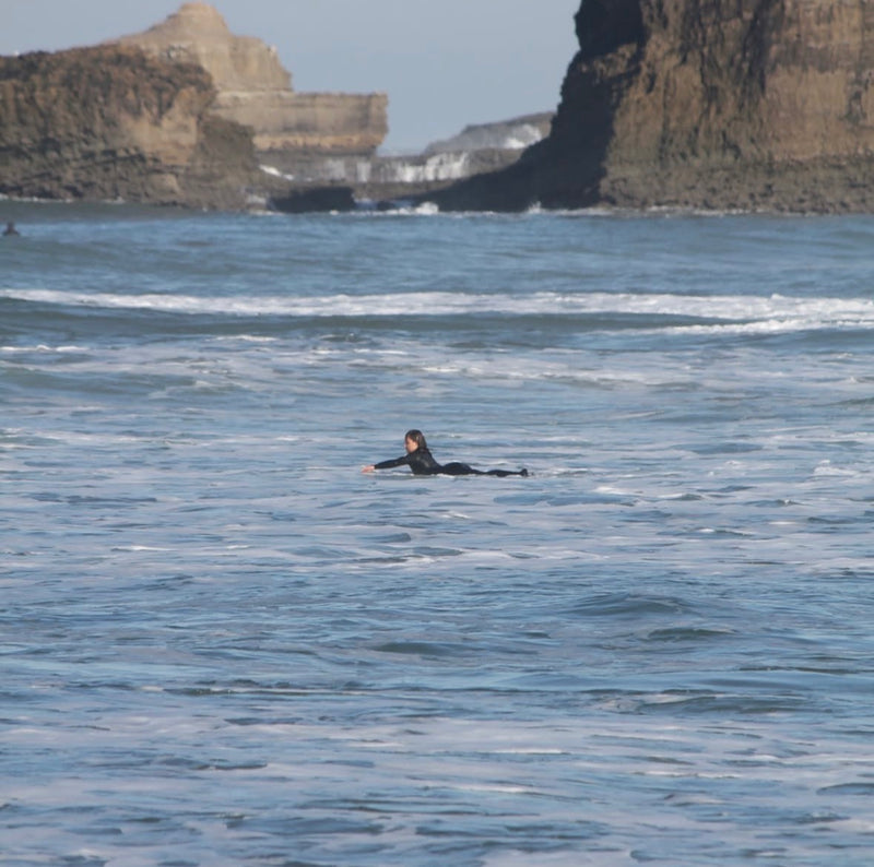 Surfer paddling out on a soft-top, beach in the Landes