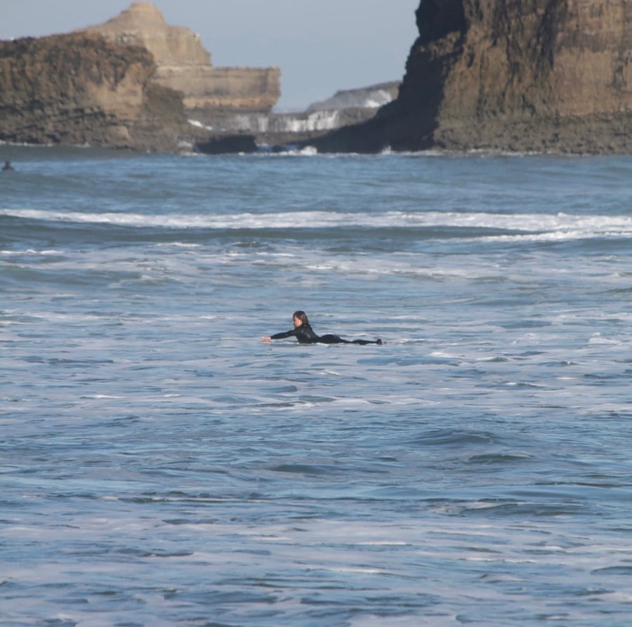 Bras d’un surfeur entrant dans l’eau pendant la rame sur un softboard