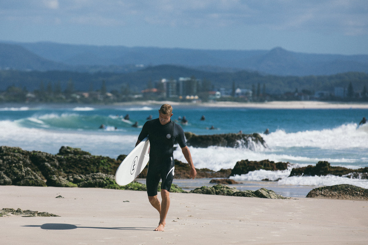 Beginner seen from behind riding a wave on a foam surfboard