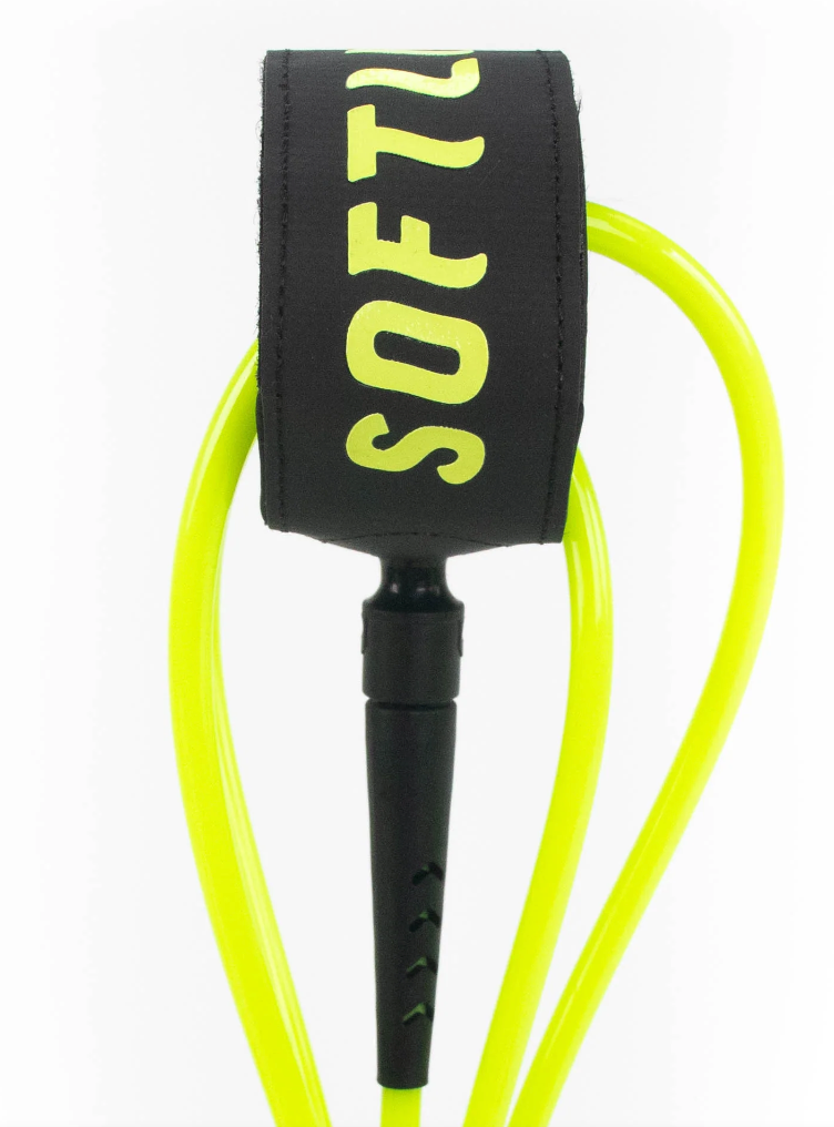 Foam surfboard and coiled leash side by side on the sand