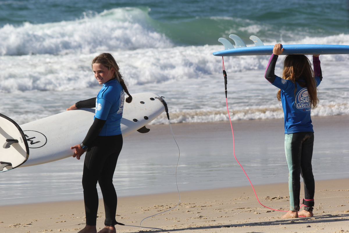 Surfer on the beach with a foam surfboard and a leash on the ankle