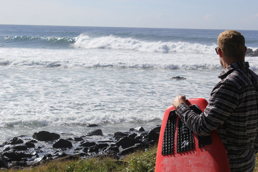 Surfer seen from behind watching the waves before paddling out