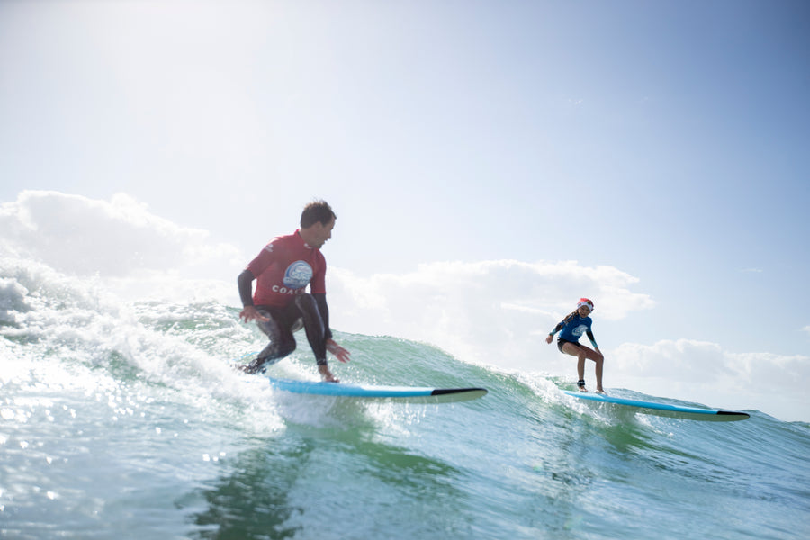 Débutant de dos dans la mousse près du bord avec une planche de surf en mousse