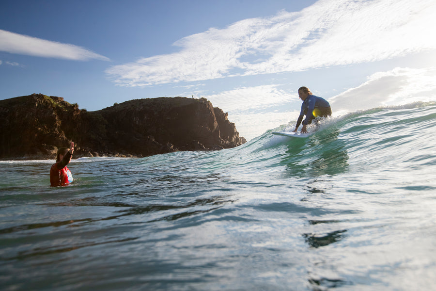Deux surfeurs de dos bien espacés au line-up sur des planches en mousse