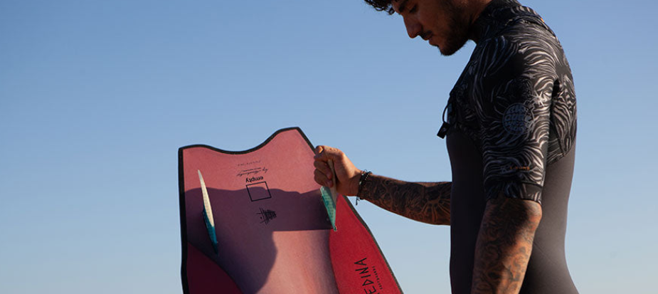 Surfeur marchant sur la plage avec une planche de surf en mousse