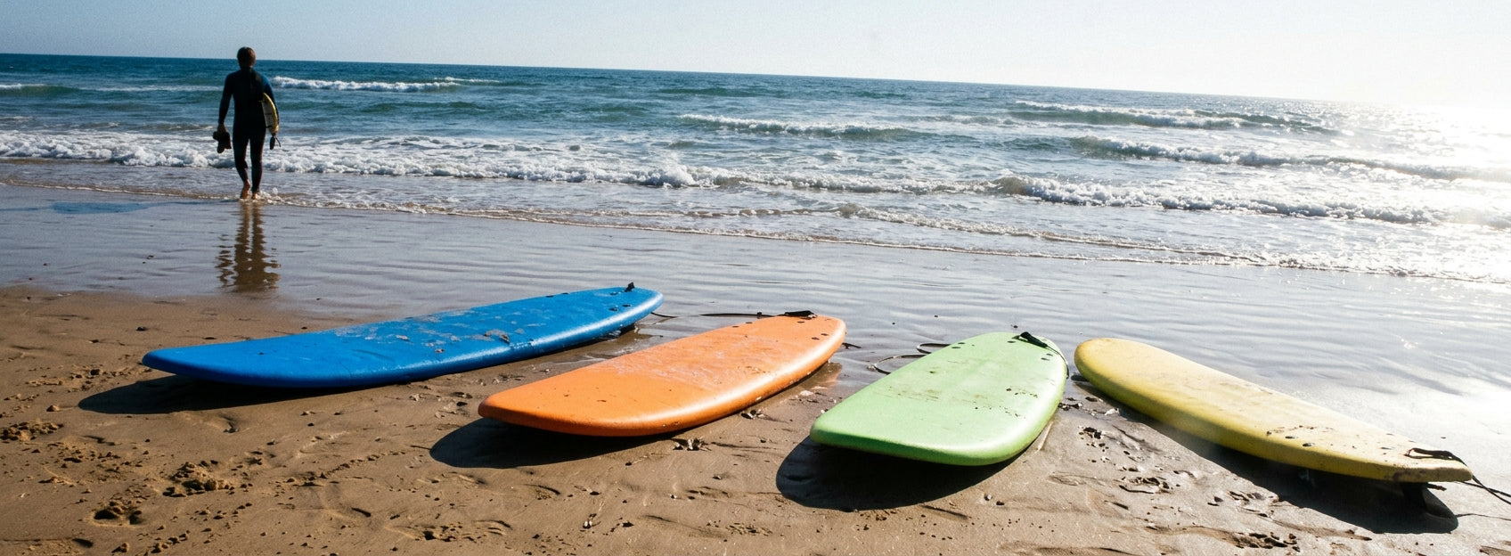 Quiver de planches de surf en mousse posées sur le sable au bord de l'eau