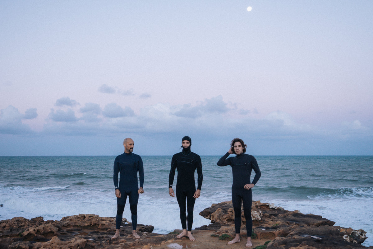 Surfer in a neoprene wetsuit walking to the water with a foam surfboard