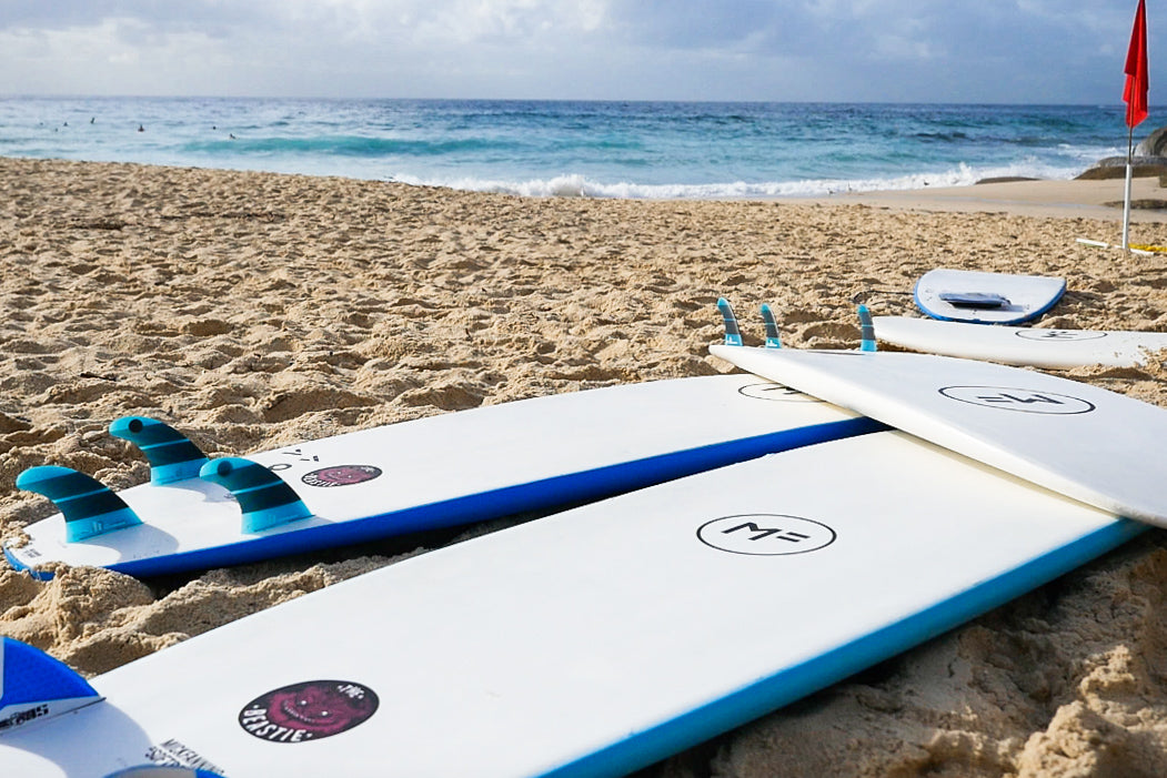 Quiver of colourful foam soft-tops standing in the sand